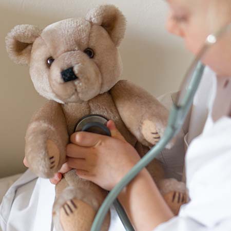 child using stethoscope on teddy bear