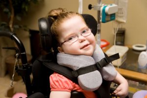 child with glasses in wheelchair with head support