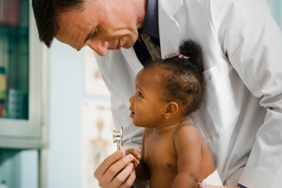 male doctor leaning over baby with stethoscope