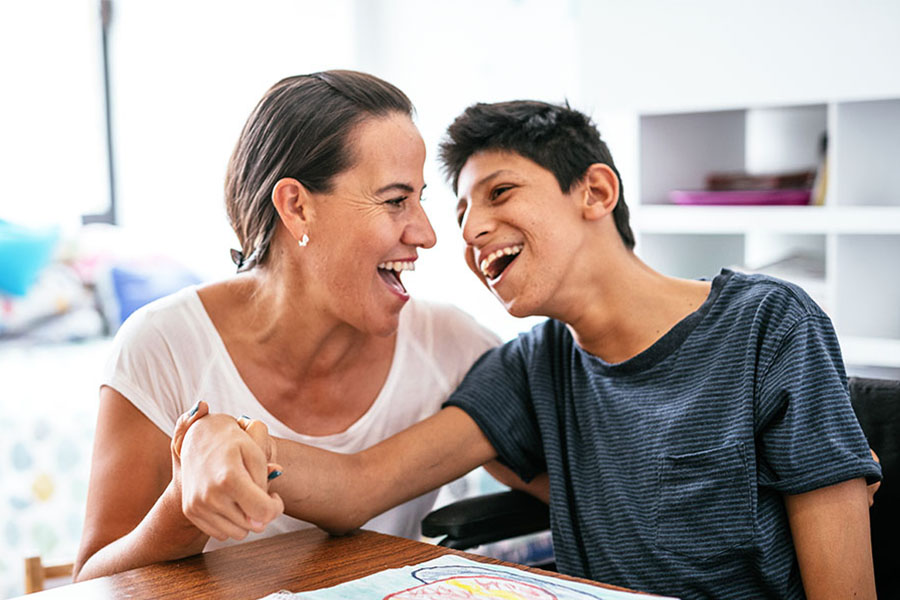 mother and teen son sitting at table laughing