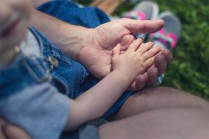 toddler sitting in adult's lap with hand in the adult's hand